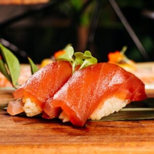 Delicious slices of salmon nigiri sushi served beautifully on a wooden platter with garnish.