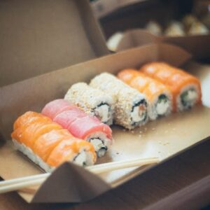 Delicious assortment of sushi rolls with salmon, tuna, and more in a takeout box. Perfect for a gourmet meal.