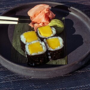 Delicious mango sushi rolls with ginger and wasabi, paired with a refreshing cocktail, set outdoors in Baghdad.