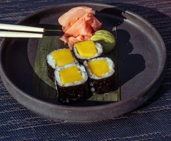 Delicious mango sushi rolls with ginger and wasabi, paired with a refreshing cocktail, set outdoors in Baghdad.