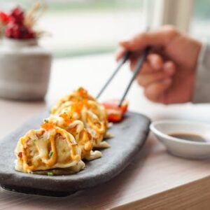 Delicious Japanese gyoza served with creamy sauce and soy dipping sauce on the side.