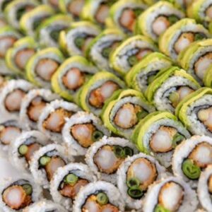 A close-up of assorted sushi rolls with vibrant veggies and seafood, freshly prepared and artfully arranged.